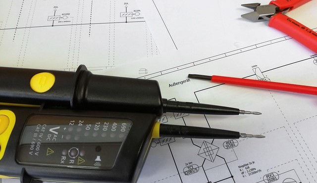 Bild mit einem Spannungsprüfer und Schraubendrehern auf einem Plan.